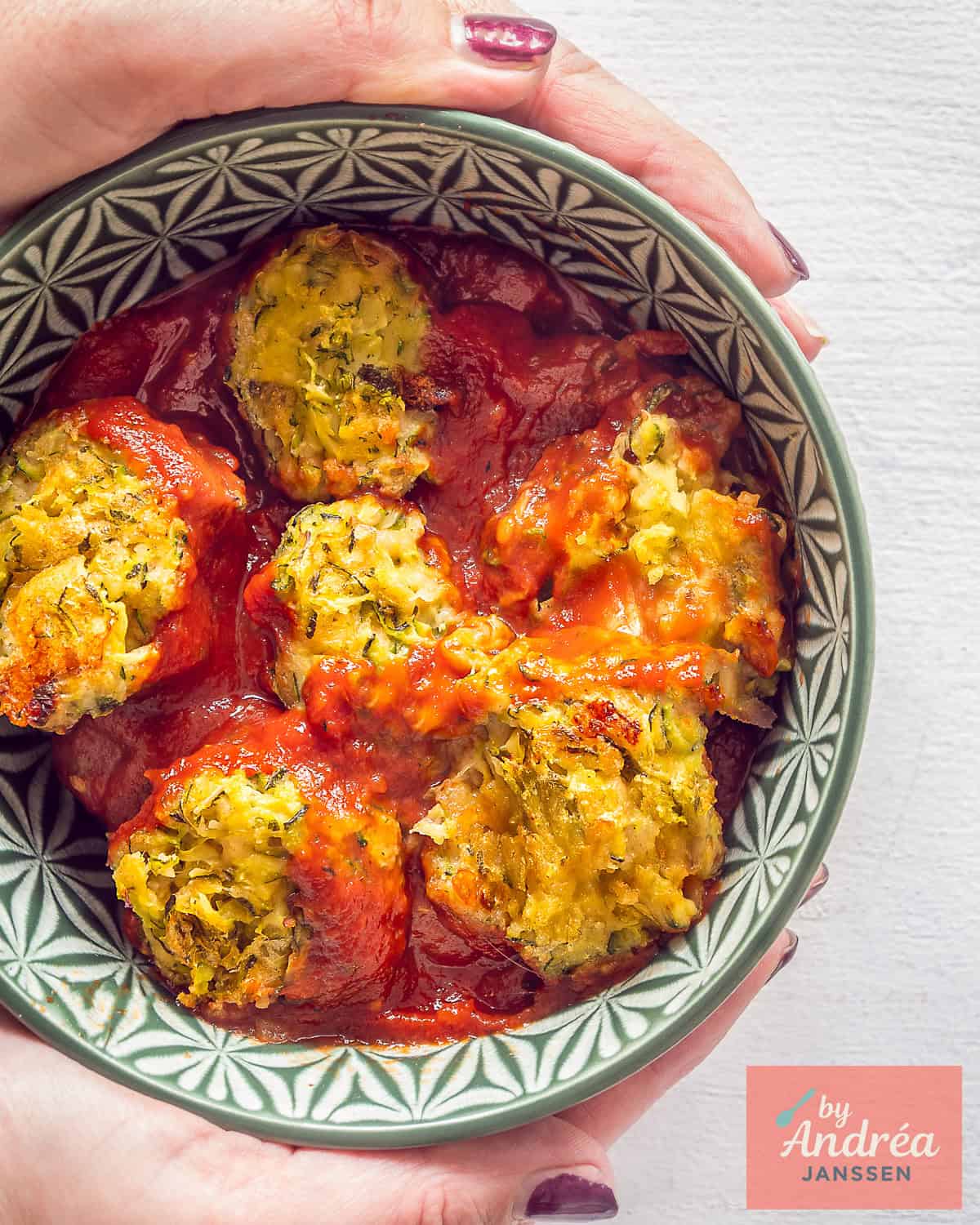 Een groene kom met vegetarische gehaktballetjes van courette in een rijke tomatensaus.