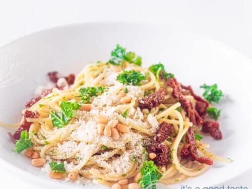 A square photo with spaghetti, sun-dried potatoes, pine nuts and cheese.