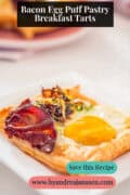 A puff pastry case filled with egg, bacon, and leek. A text at the top reads: Bacon Egg Puff Pastry Breakfast Tarts