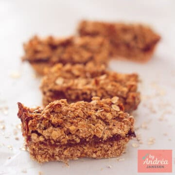 A square photo with four oatmeal bars filled with dates placed one after the other.