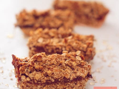 A square photo with four oatmeal bars filled with dates placed one after the other.