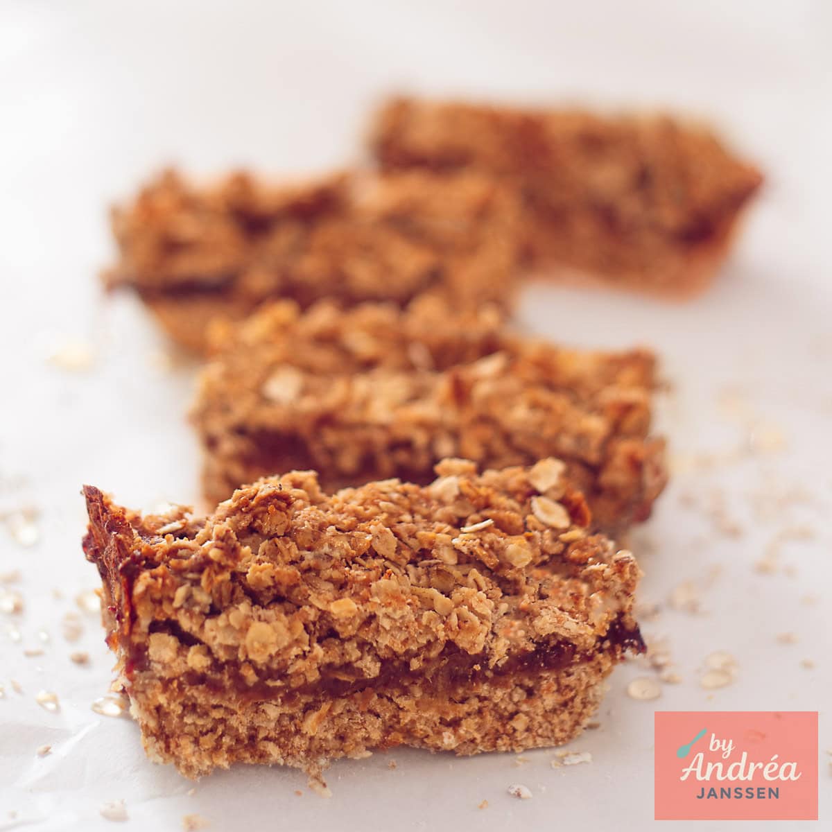 A square photo with four oatmeal bars filled with dates placed one after the other.