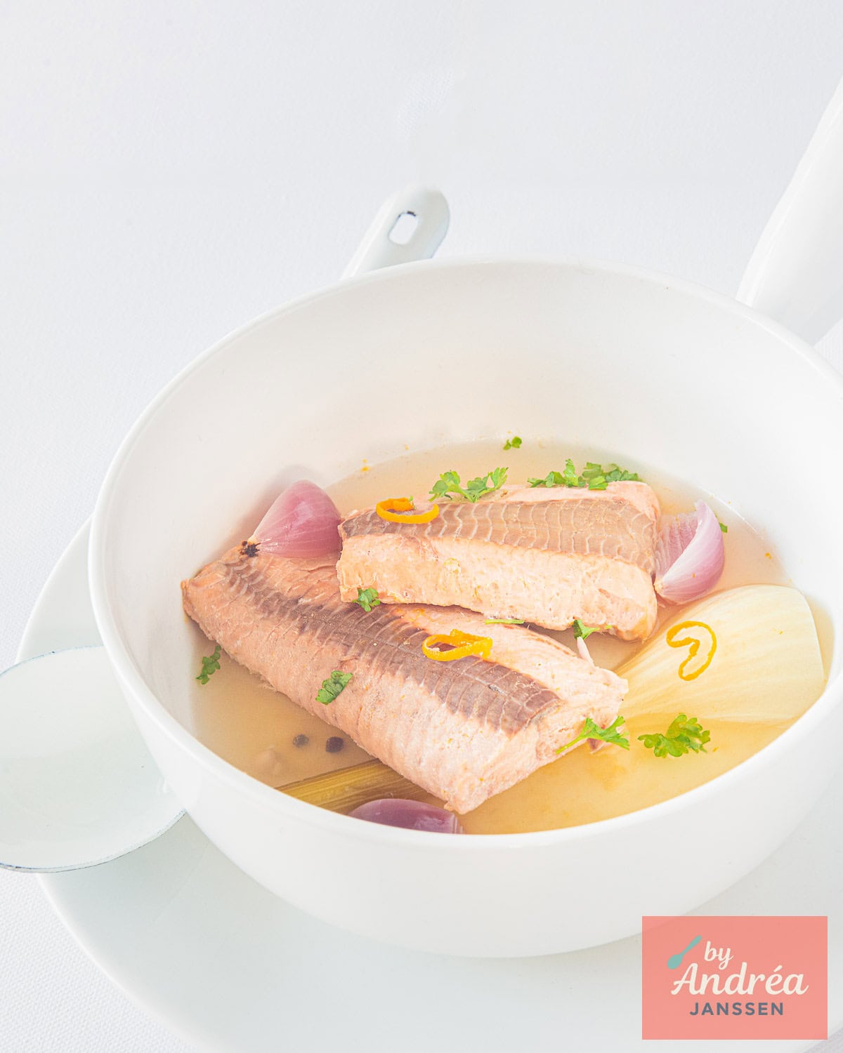 Een witte schaal met Gepocheerde Zalm met Witte Wijn in 20 Minuten in het pocheervocht.