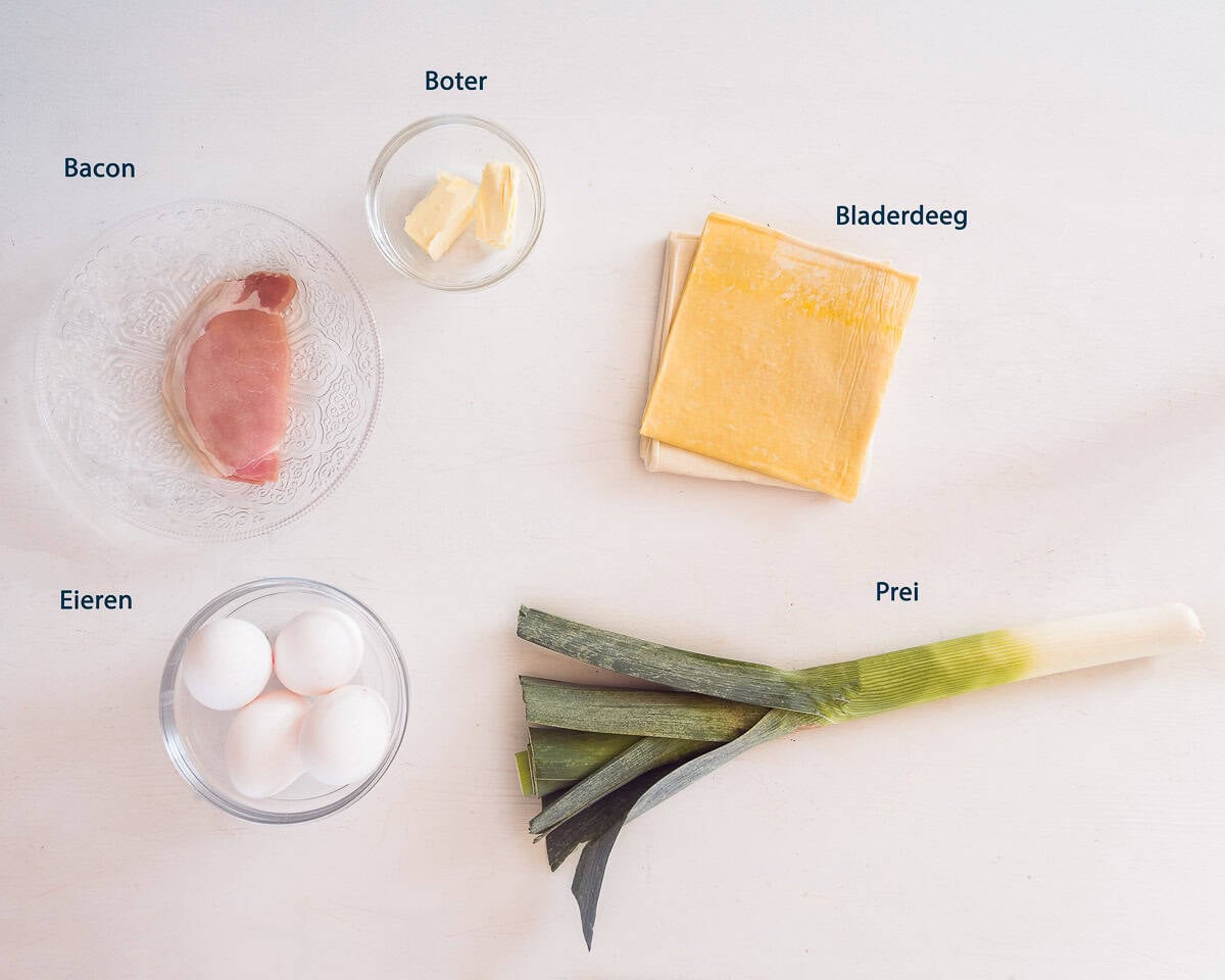 Ingrediënten Bladerdeeg Bakjes met Ei Prei En Bacon op een witte ondergrond met tekstbeschrijving.