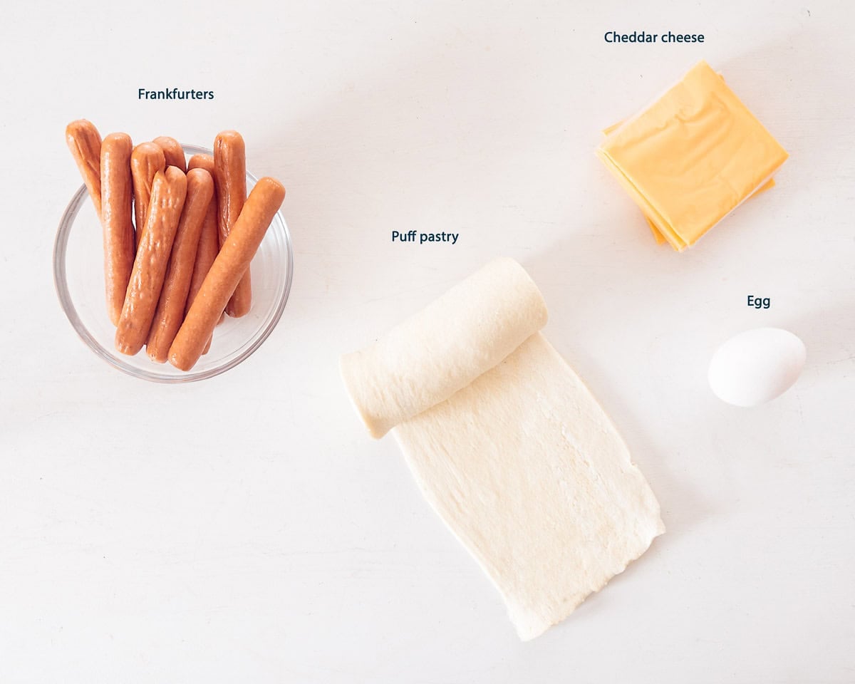 Ingredients Cheesy Pigs in a Blanket on a white background with text description