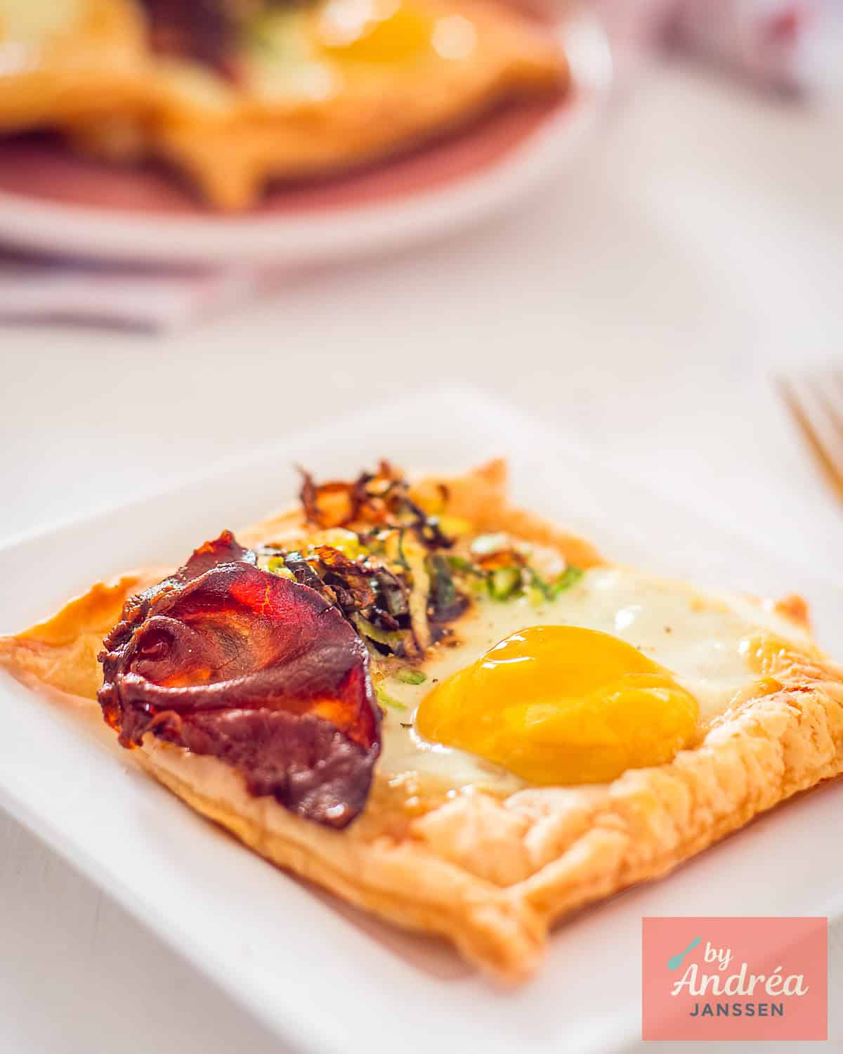 In the foreground a bowl of puff pastry with bacon, fried egg and leek.