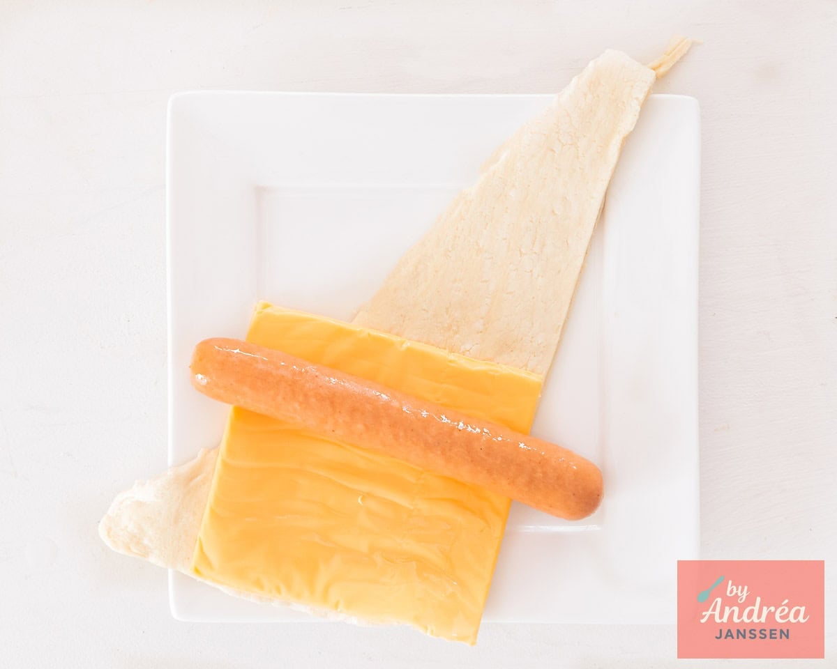 On top of the puff pastry a sheet of cheddar cheese and a frankfurter