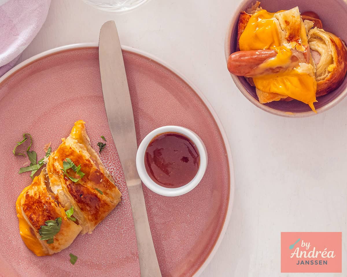 Baked and sliced cheesy pigs in a blanket with ketchup.