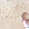 Cookies are cut out of the dough with a heart cutter.