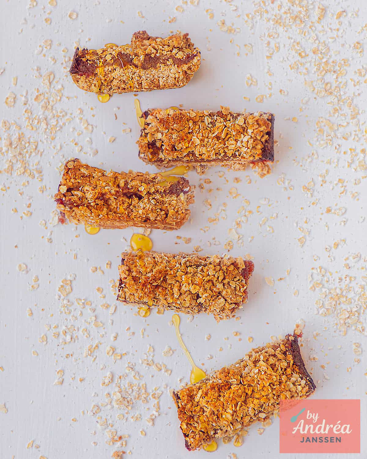 A top-down photo of 6 date oatmeal lemon bars on a white background.