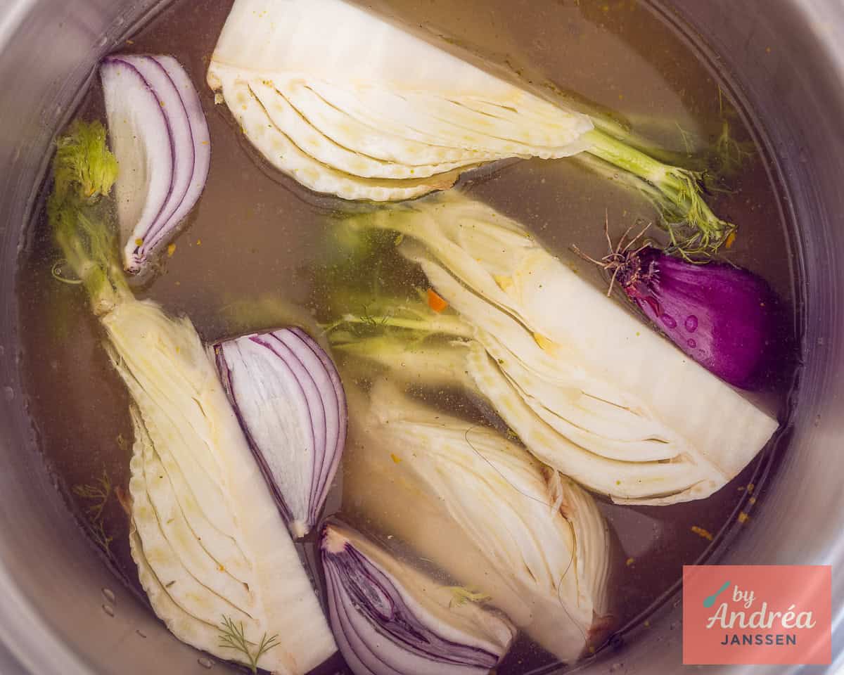 Groenten, sinaasappel en peper met bouillon in een pan.