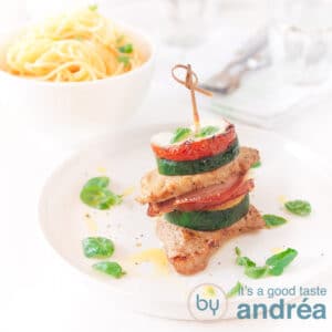 A square photo with a plate with open saltimbocca and a bowl of spaghetti in the background