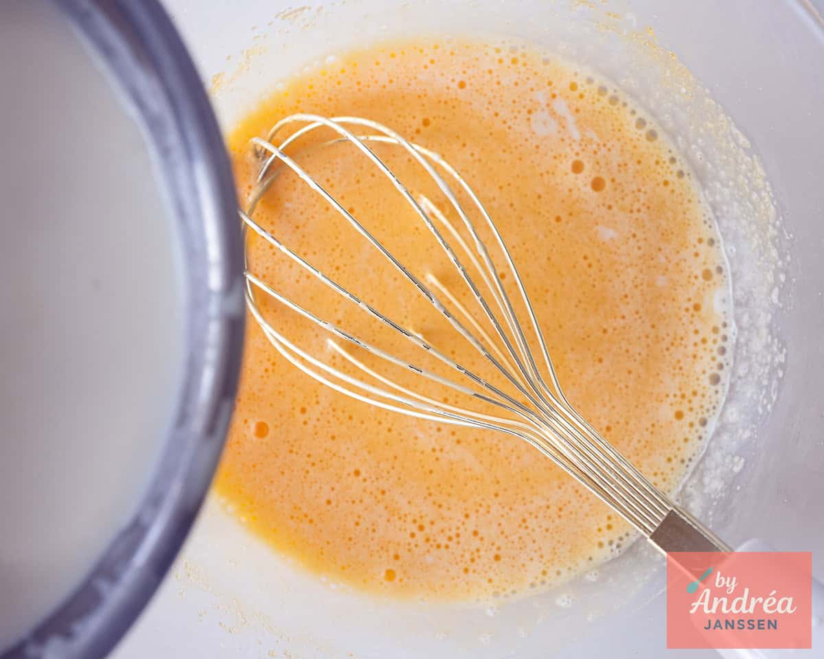 Beaten eggs with a whisk. Cream is poured into the bowl.