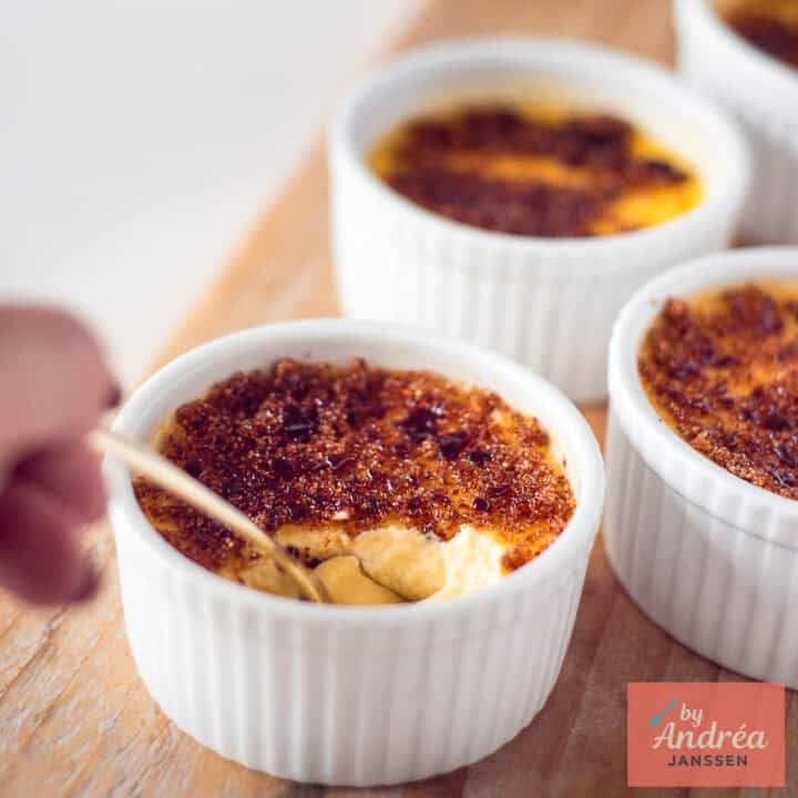 A square picture with three ramekins with creme brulee with honey and cinnamon. A bite taken out of the ramekins