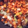 A slow cooker filled with ribs, carrot, celery and onion cubes.