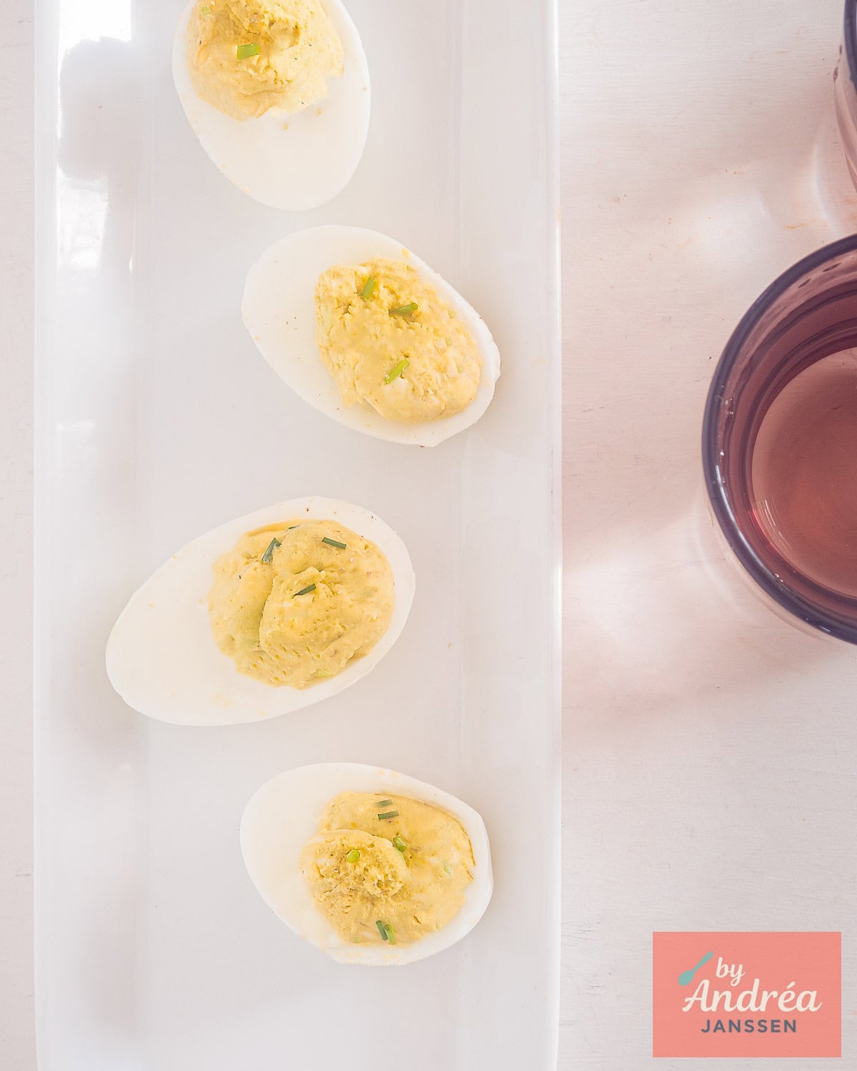 A picture from above: a white plate with four deviled eggs filled with avocado egg yolks cream.