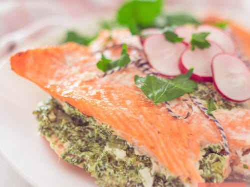 A square photo of a portion of a salmon fillet filled with a creamy spinach filling