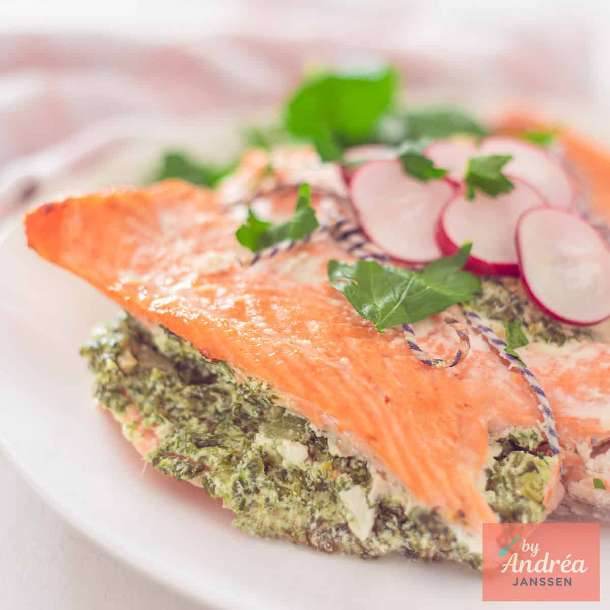A square photo of a portion of a salmon fillet filled with a creamy spinach filling