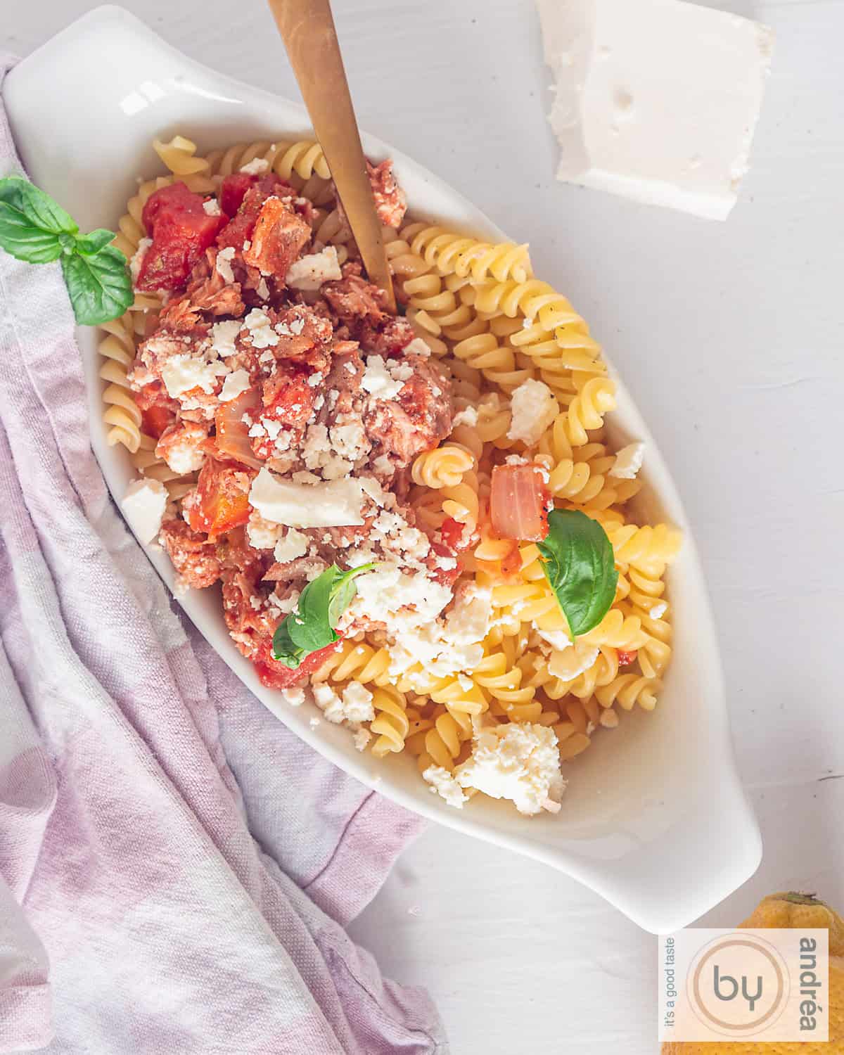 Een foto van bovenaf van een wit schaaltje met pasta, tonijn, feta en tomatensaus.