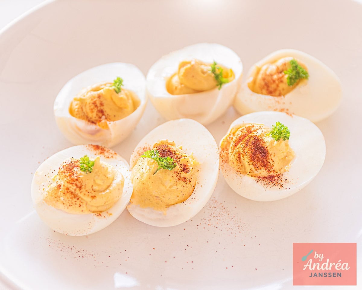 A platter full of curried deviled eggs with garnish