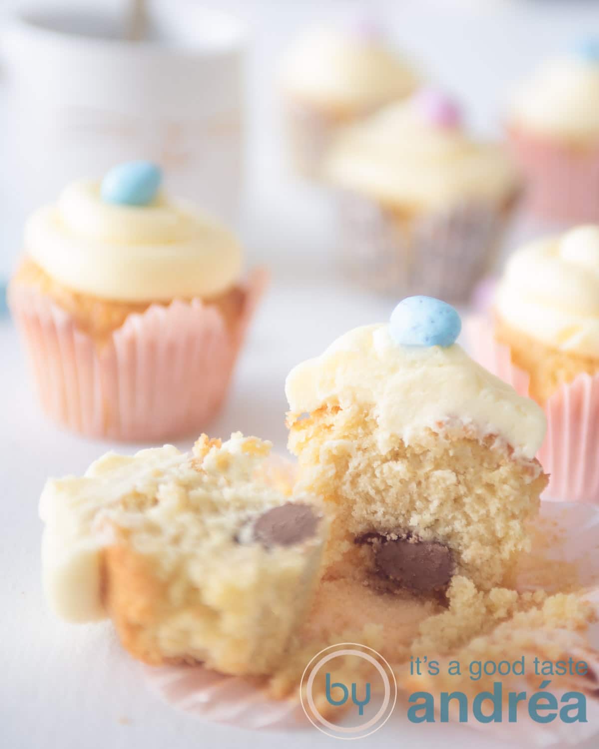 a bunch of easter cupcakes on a white background. One cupcake is halved and you can see a chocolate egg.