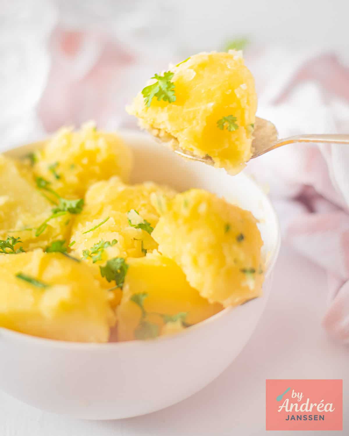 A white bowl with boiled potatoes and parsley