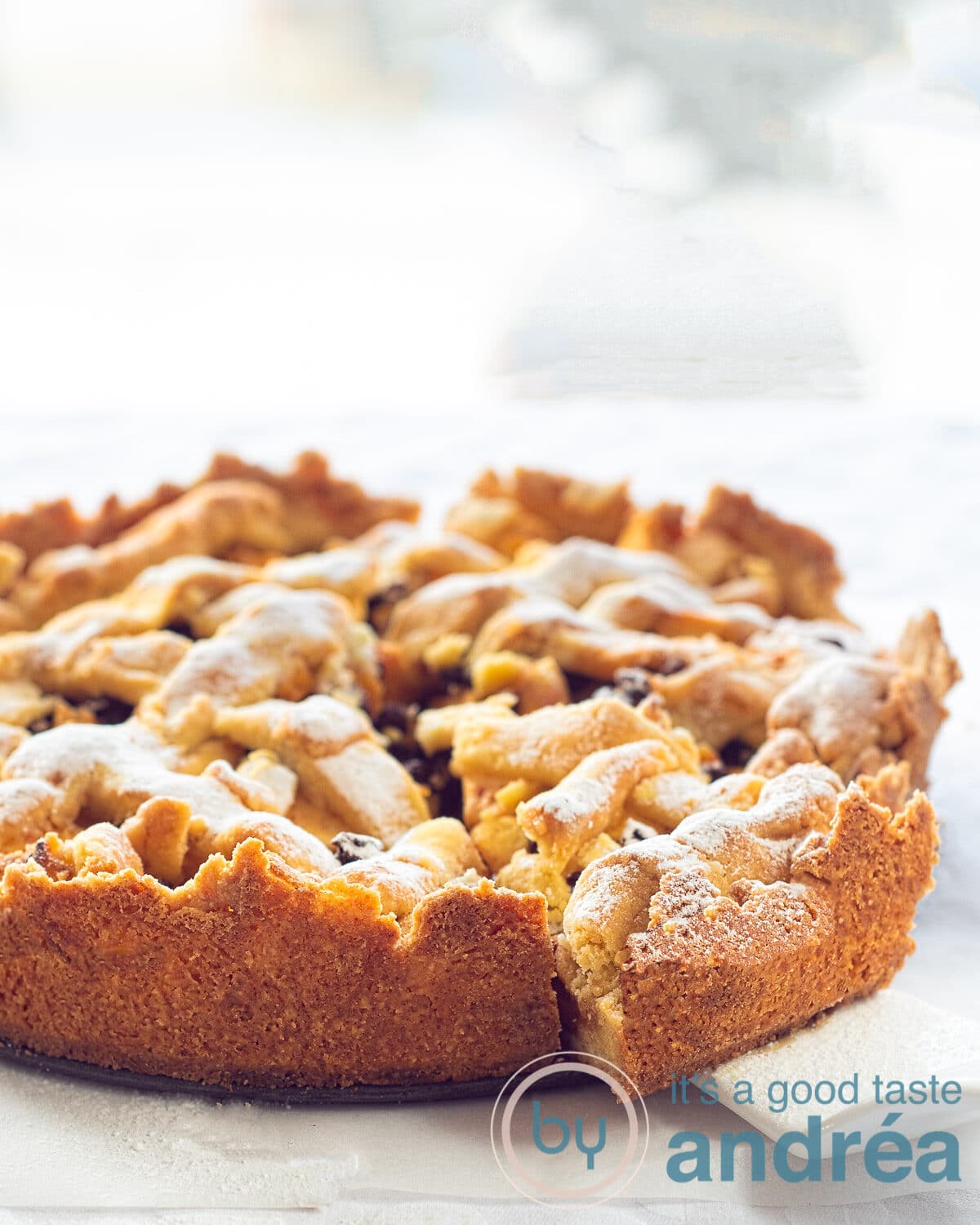 A Dutch apple pie in a light background. A slice is taken out of it