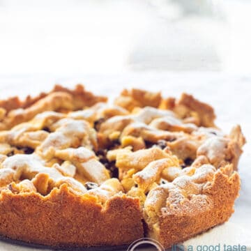 A Dutch apple pie in a light background. A slice is taken out of it