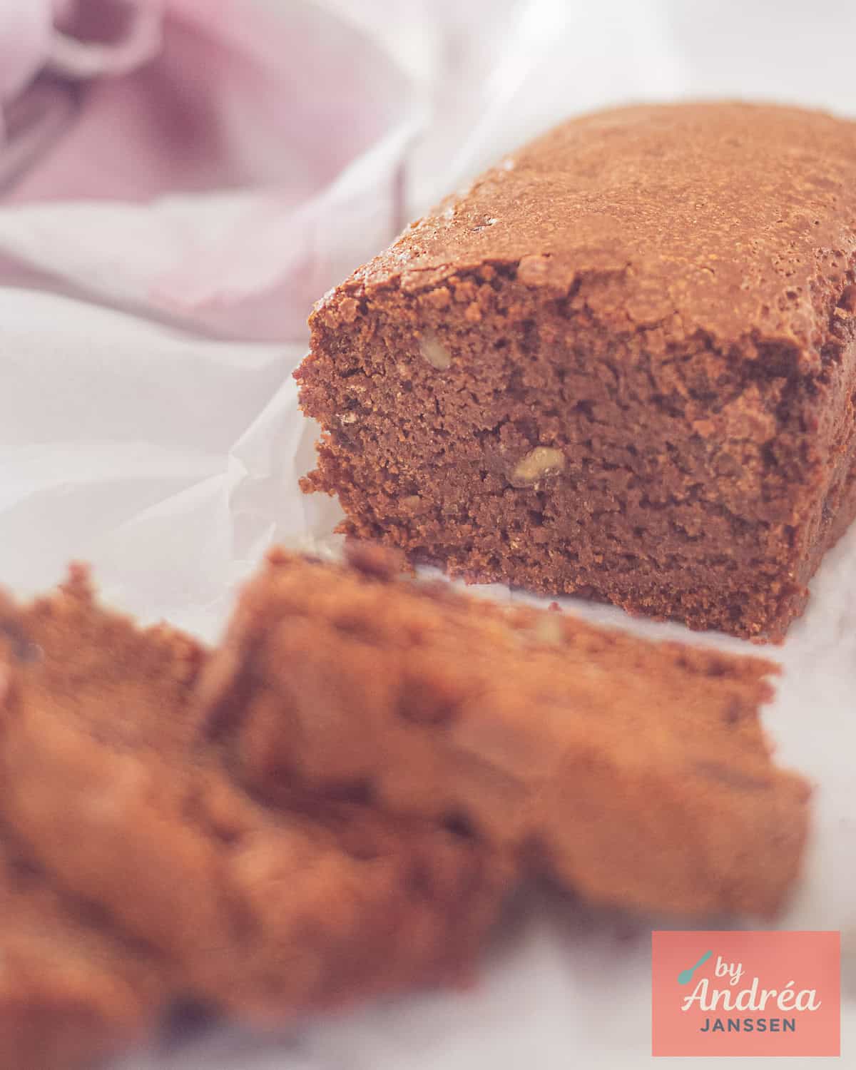 A piece of gingerbread from which three slices have been cut, and where you can see the kruidkoek gingerbread topped with raisins and nuts.