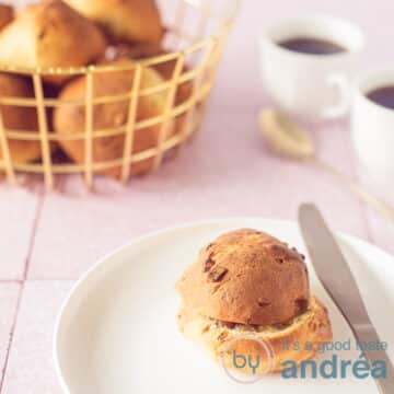 A plate of a walnut roll with orange rolls with walnuts in the background in a basket.