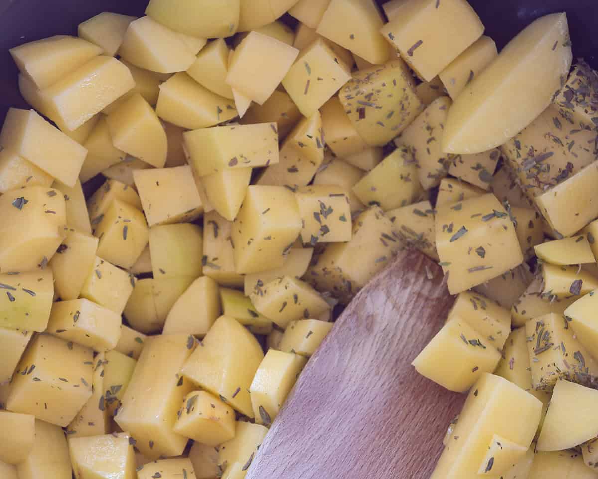 A wok with diced potatoes and herbs