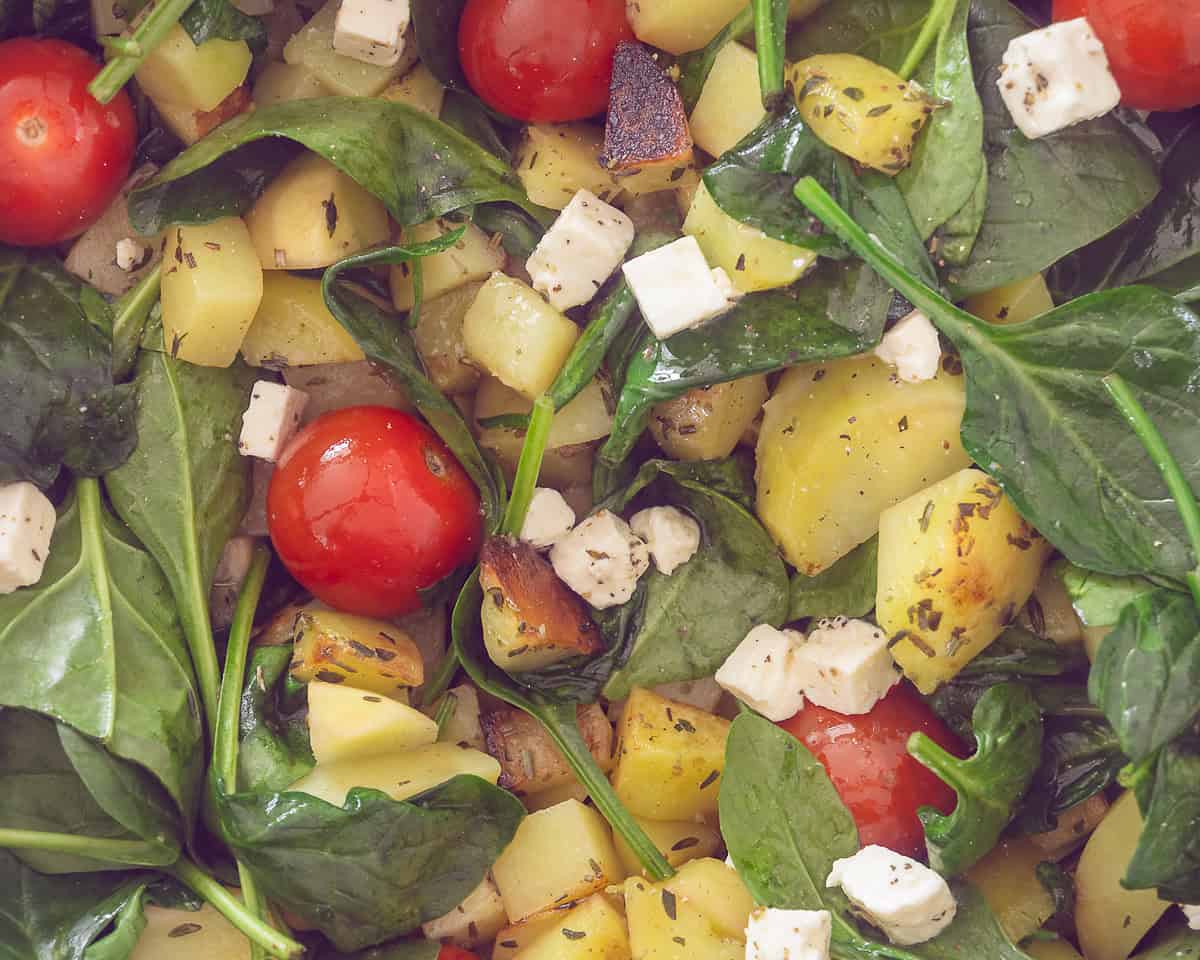 A pan with potatoes, feta, cherry tomatoes, herbs.