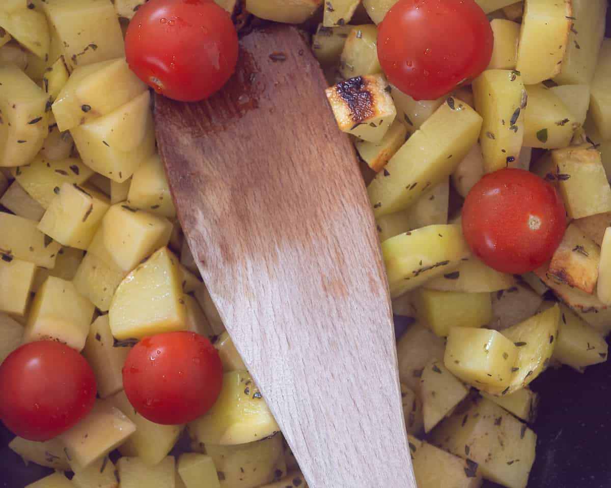 Potatoes, herbs and cherry tomatoes in a pan
