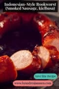 Indonesian Kielbasa on a dark background. A text on top: Indonesian-Style Rookworst (Smoked Sausage, kielbasa)