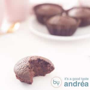 A square photo with a cupcake with chocolate in the front with a bite out. In the background another plate with lactose-free cupcakes.