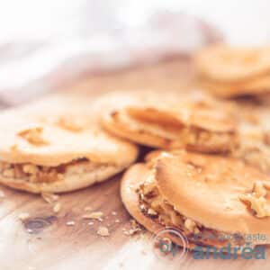 A square photo with a wooden background with three pita breads filled with goat cheese, honey and walnut dip. A pink white tea towel in the background.