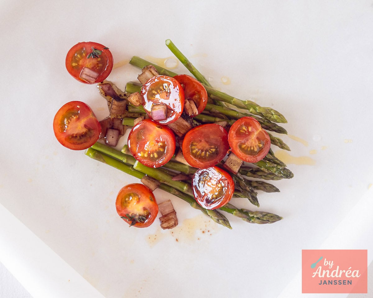 Baking paper with green asparagus and cherry tomatoes