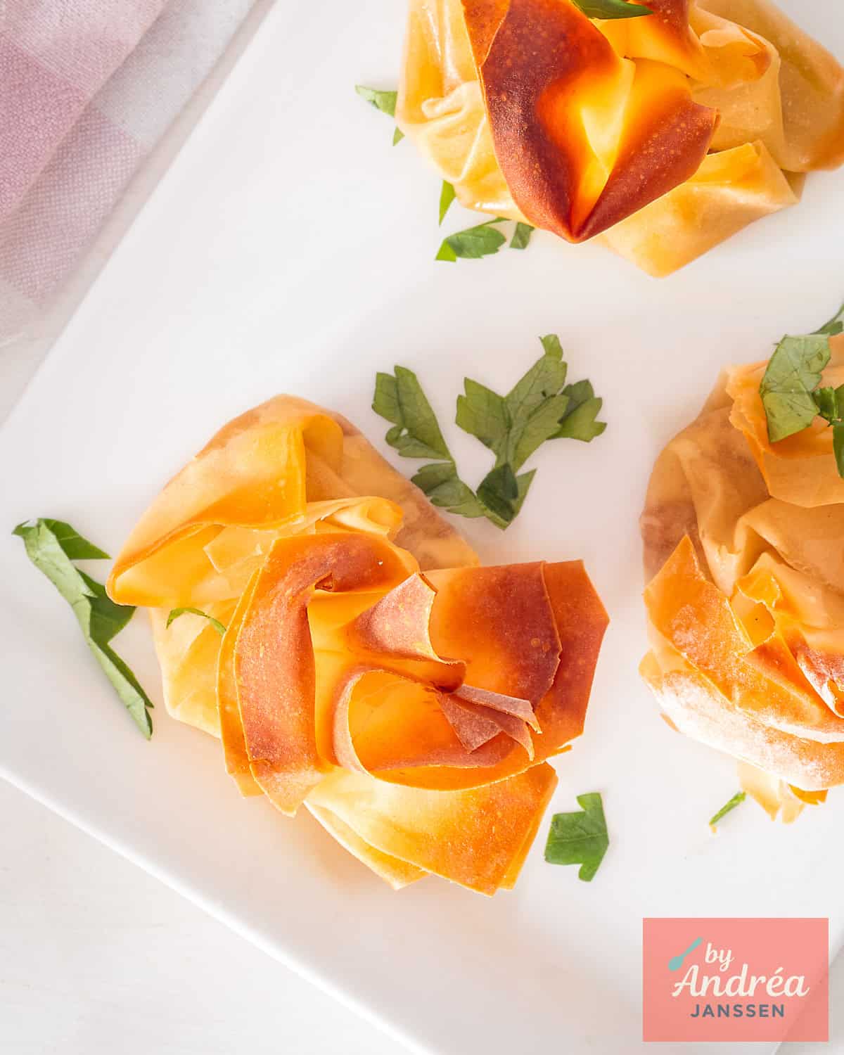 A picture from above of three appetizers with goat cheese, honey and walnuts wrapped in phyllo dough.