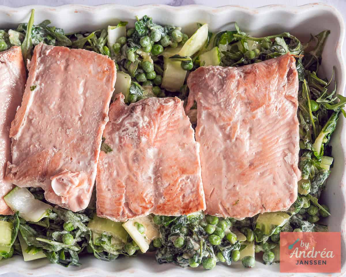 Groene groenten en stukken zalm in een ovenschaal