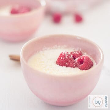 A square photo with two pink bowls of creamy lemon custard with raspberry