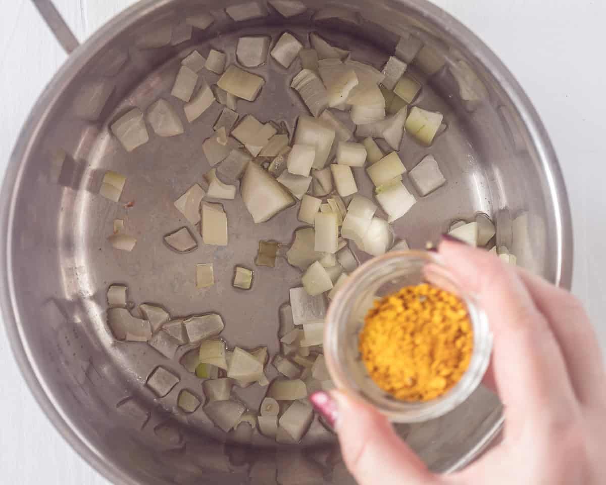 A pan with onions where a curry spice mix is added.