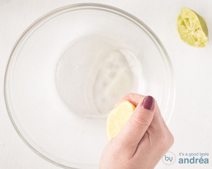 A lemon is squeezed into a glass bowl