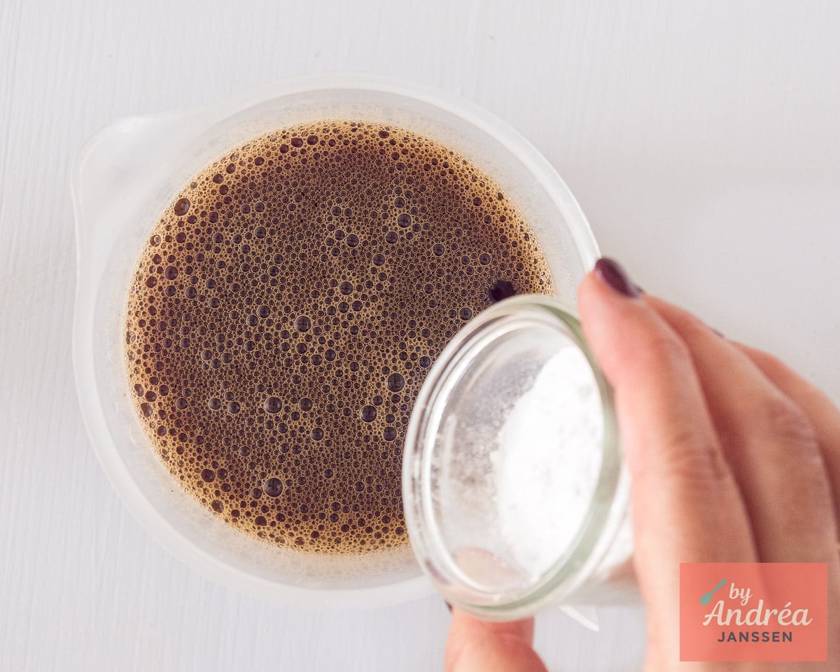 Confectioners sugar being added to a jug of strong coffee for creamy iced coffee