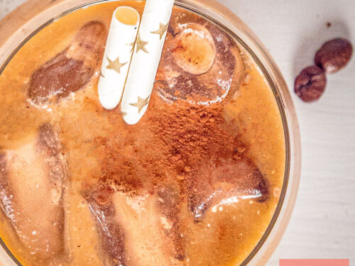 Top-down view of iced coffee with ice cubes and a dusting of cocoa powder