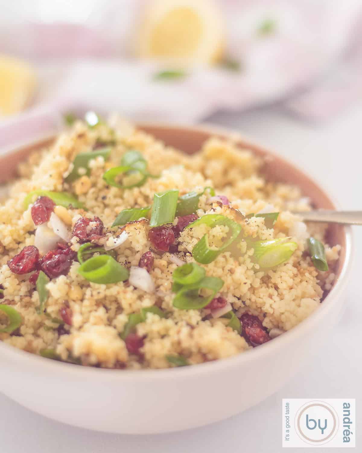 Een roze kom met couscous, cranberry's, citroen, pijnboompitten