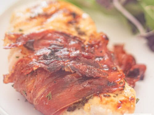 A square photo of a chicken fillet with Italian herbs wrapped in Serrano ham