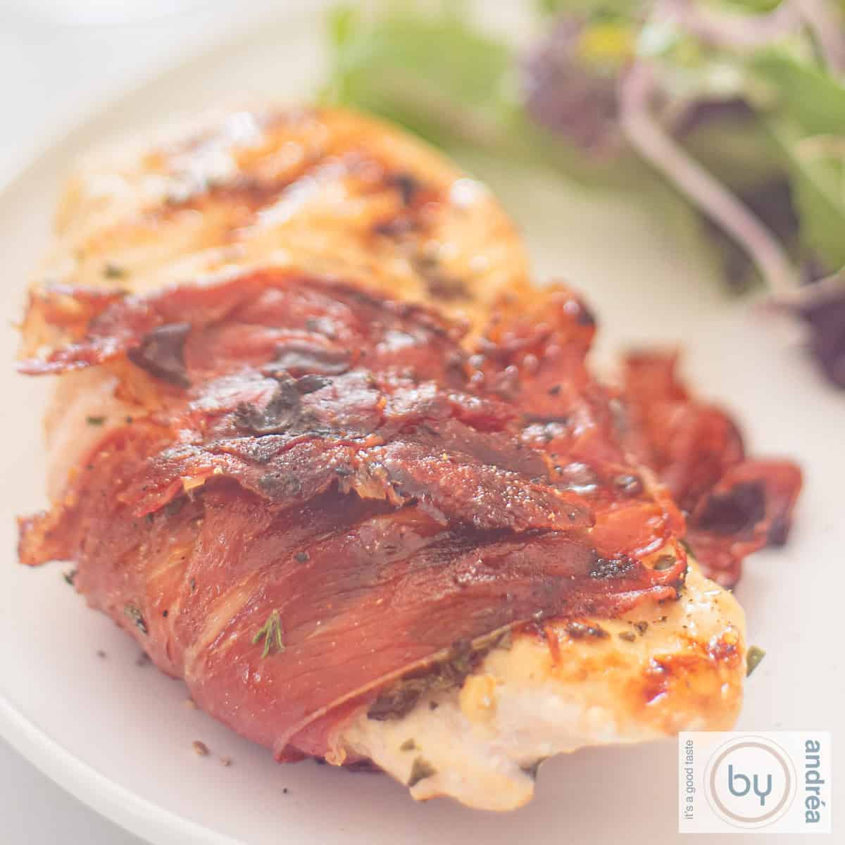 A square photo of a chicken fillet with Italian herbs wrapped in Serrano ham