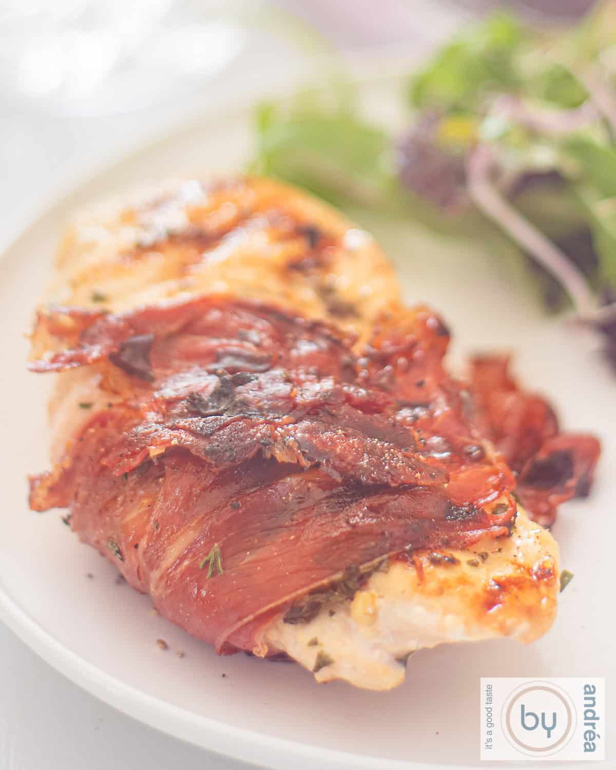 Een wit bord met kipfilet met serranoham en Italiaanse kruiden van de BBQ