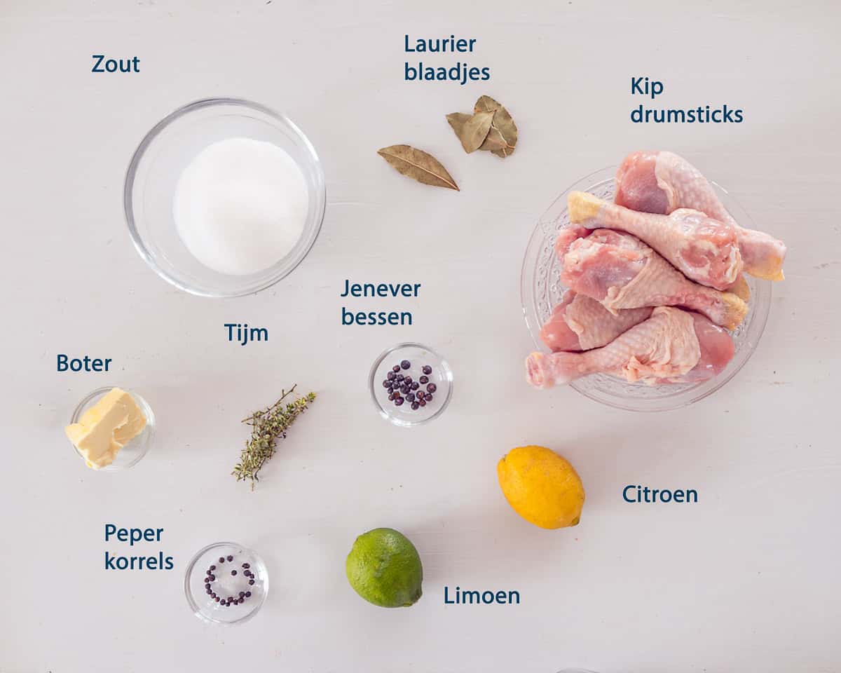 ingredienten Gepekelde kip drumsticks met citroen en gin op een lichte ondergrond met tekstbeschrijving