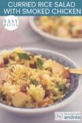 A portion of a gray bowl containing a curried rice salad with smoked chicken, raisins, and walnuts. A caption at the top reads: Easy recipe, Easy Curried Rice Salad With Smoked Chicken